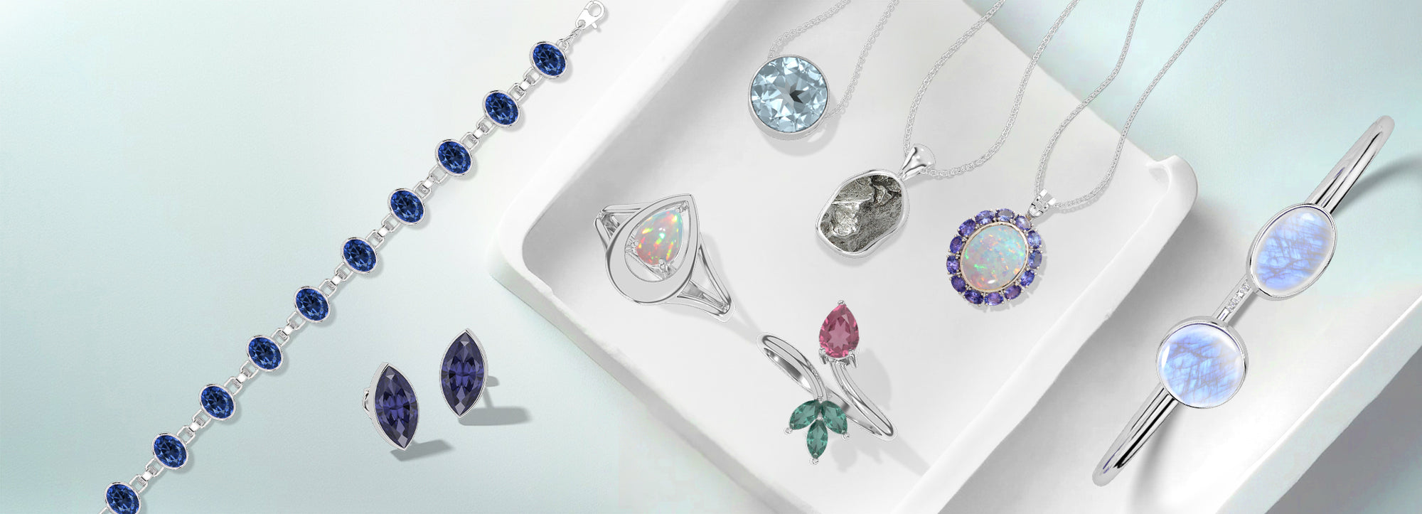 Silver gemstone jewellery arranged on a white tray